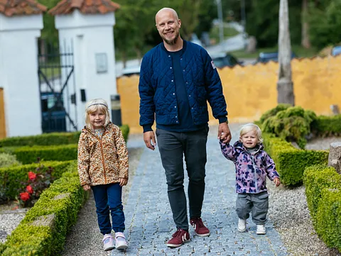 Far med to døtre på vej til kirke