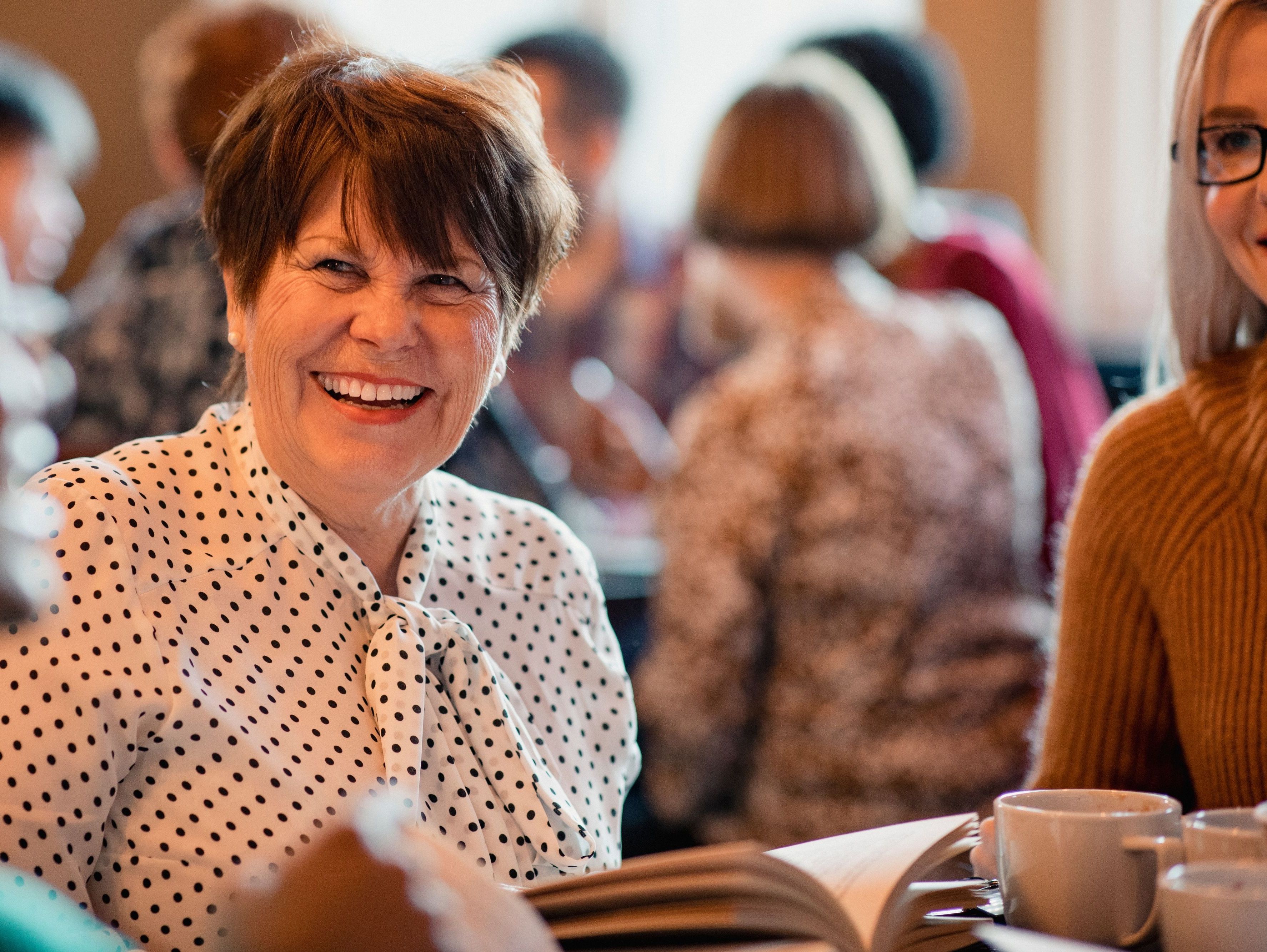 Kvinde sidder med en bog og taler med andre